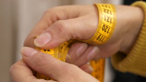 Close-up-of-tape-measure-in-woman-hands.-Slow-motion