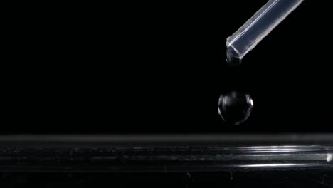 Close-up-on-medical-science,-drop-of-liquid-exit-a-pipette,-black-background