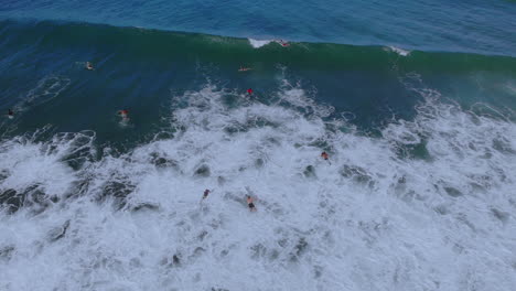 Zwei-Surfer,-Die-An-Einem-Klaren-Tag-Mit-Blauem-Himmel-Unter-Eine-Welle-Gehen,-Die-Im-Blauen-Ozean-In-Puerto-Rico-Abstürzt