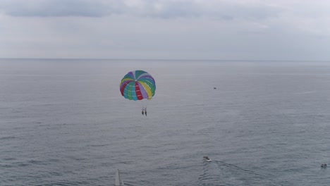 A-panning-view-of-people-parasailing-over-a-beautiful-calm-ocean-on-a-cloudy-day