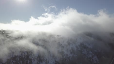 Aerial-view-of-clouds-rolling-over-a-mountain-on-a-sunny-day