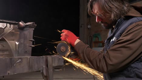 Sparks-fly-off-circular-saw-as-man-cuts-metal-in-workshop,-Medium-Shot