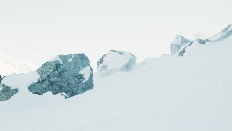 Seitenansicht-Eines-Mannes,-Der-An-Einem-Kalten-Wintertag-Zwischen-Felsen-An-Der-Kamera-Vorbei-Ski-Fährt