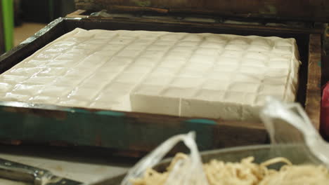 Hands-picking-raw-fresh-tofu-from-wooden-container