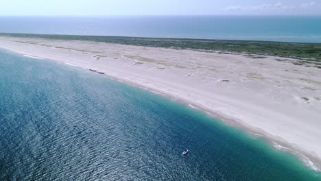 Drone-flying-around-a-boat-in-emerald-water-on-the-coast-of-a-national-wildlife-preserve