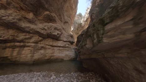 Extreme-low-angle-shot-of-fpv-drone-flying-between-canyon-rocky-walls