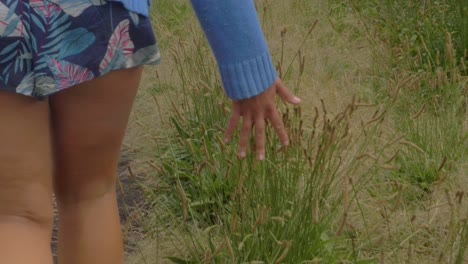 Sexy-Girl's-Hand-Feeling-And-Touching-Tall-Grass-While-Walking-At-Track-In-Crescent-Head,-NSW,-Australia
