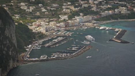 Aerial-view-of-a-ferry-and-other-boats-arriving-in-Marina-Grande-port,-in-Capri