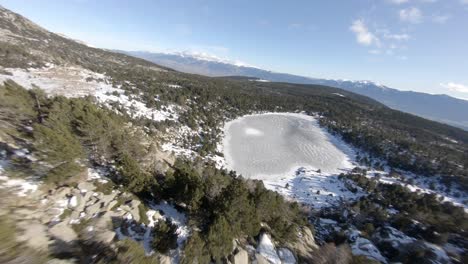 Spectacular-high-speed-aerial-fpv-drone-approach-over-iced-lake-in-mountain