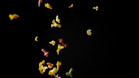 Colorful-uncooked-pasta-flying-on-black-background.-Slow-motion