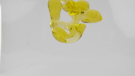 Yellow-color-vegetable-oil-pouring-into-water-forming-bubbles