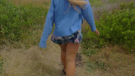 Girl-In-Blue-Sweater-Walking-With-Hair-Blowing-In-The-Wind---Track-At-Crescent-Head-Lookout-And-Big-Nobby-In-Sydney,-NSW,-Australia