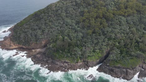 Waves-Crash-Against-Rocky-Coast-Of-Mount-Yacaaba-Headland-With-Green-Forest---Hawks-Nest,-NSW,-Australia