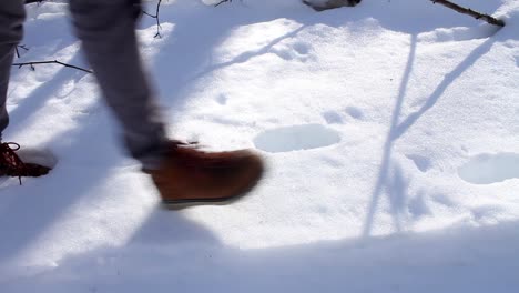 Hombre-Con-Botas-Marrones-De-Invierno-Caminando-Sobre-Nieve-Profunda-Durante-El-Día---Tiro-De-ángulo-Bajo