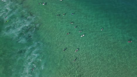 Top-View-Of-Surfers-Floating-On-Their-Surfboards-At-Bondi-Beach-In-The-Australian-City-Of-Sydney,-aerial