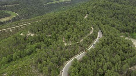 Cars-driving-through-a-green-forest-with-multiple-windy-roads