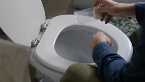 Ausgeschnittene-Ansicht-Eines-Mannes,-Der-Kokain-In-Einer-Toilettenschüssel-In-Einer-Modernen-Toilette-Ausgießt---Nahaufnahme