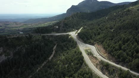 Aerial-View-Of-Old-White-Car-Fast-Driving-In-The-Forest-Road-During-Daytime---drone-shot