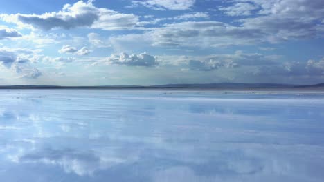 Low-Aerial-view-of-salt-lake,-reflecting-the-blue-sky-and-the-clouds