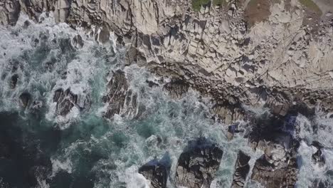 Foamy-Sea-Waves-Crashing-On-Rocky-Cliff-Along-The-Coast-In-California---aerial-orbit