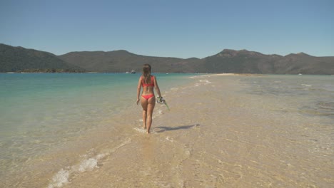 Back-View-Of-A-Girl-Walking-On-Sand-Bar-Across-Langford-Island,-Whitsundays-Islands,-QLD-Australia