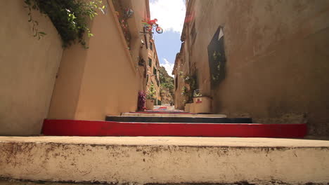 low-angle-sliding-shot-of-an-old-painted-alley-on-a-sunny-day-in-a-Mediterranean-town