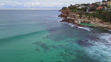 Tourists-Ride-The-Big-Ocean-Waves-Near-The-Rock-Pool-At-Bronte-Beach,-Australia