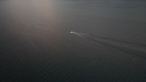 Schöne-Luftaufnahme-Des-Comer-Sees-Mit-Boot-In-Italien,-Mit-Klarem-Wasser-Und-Kleinen-Wellen,-Die-Bei-Sonnenuntergang-In-4k-Schwimmen