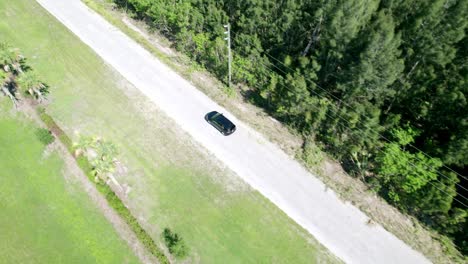 Aerial-shot-of-car-riding-through-empty-rural-road
