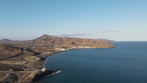 Video-Aéreo-De-Drones-De-Un-Pequeño-Pueblo-En-El-Lado-Costero-De-La-Isla-Fuerteventura-Mientras-Se-Pone-El-Sol