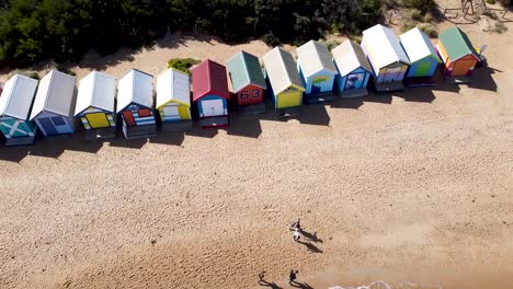 Aerial---drone-shot-of-a-row-of-bright-and-colorful-beach-shacks,-Australia