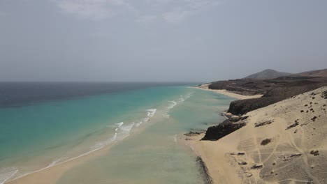 Luftdrohnenaufnahme-Eines-Wunderschönen-Strandes-Mit-Klarem-Wasser-In-Fuerteventura-Auf-Den-Kanarischen-Inseln