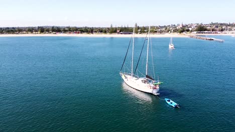 Aerial---drone-shot-of-yacht-anchored-off-the-shore-of-an-Australian-town