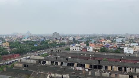 Vista-Aérea-épica-De-La-Magnífica-Ciudad-De-Kolkata-Con-Vía-Férrea,-Antiguas-Fábricas-Cerradas-Y-Tren-En-Movimiento