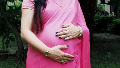 Mujer-Embarazada-En-Sari-Sintiéndose-Feliz-Al-Aire-Libre-Mientras-Cuida-A-Su-Hijo