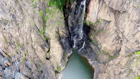 Aerial---Waterfall-cascades-down-rock-face-to-create-hidden-lake