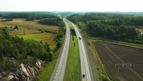 4K-Ascending-aerial-view-revealing-4-lane-highway-with-cars-and-trucks-passing-both-directions-during-hazy-summer-morning-sunlight