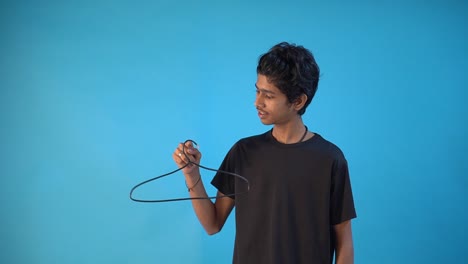 Young-Indian-man-in-black-t-shirt-playing-with-hanger