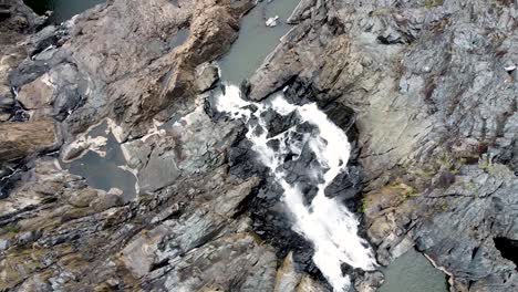 Aerial---Bird's-eye-view-of-waterfall-tumbling-down-rock-face-to-create-rock-pools