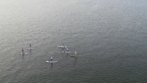 Stand-Up-Paddle-Boarding-On-A-Peaceful-Ocean-With-Vacationists-On-Summer-Holiday