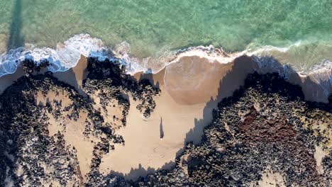 Aerial:-Birdseye-view-of-person-sitting-on-beautiful-isolated-beach