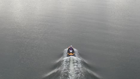 Aerial-View-Of-A-Person-Riding-Along-The-Lake-On-A-Personal-Watercraft