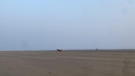 Slow-motion-shot-of-the-sand-in-the-beach-with-a-boat-in-a-natural-background-of-sky