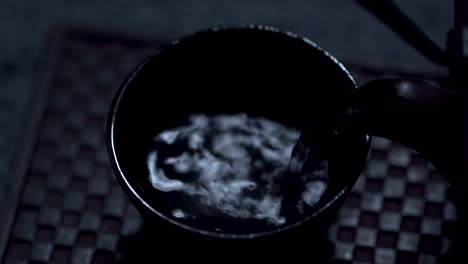 Orientalische-Teekanne-Aus-Gusseisen,-Die-Im-Mondlicht-Tee-In-Eine-Tasse-Gießt