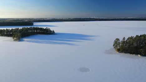 Forward-moving-aerial-over-frozen-lake-with-forest-islands