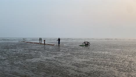 Pov-Silhouette-Gimble-Shot-Eines-Angenehmen-Abends-Am-Strand-In-Kalkutta-Mit-Einem-Fischer,-Der-An-Seinen-Netzen-Arbeitet,-Und-Einem-Passanten,-Der-Steht-Und-Das-Meer-Betrachtet
