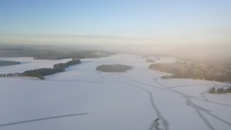Sich-Vorwärts-Bewegender-Luftblick-über-Den-Zugefrorenen-See-Mit-Waldinseln-Und-Natürlichen-Linienmustern-Auf-Eis