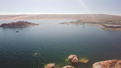 A-dolly-aerial-shot-of-a-great-body-of-water,-a-beautiful-lake-in-the-mid-west-with-lots-of-orange-rocks-mid-day