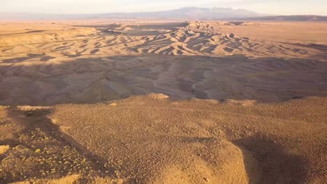 A-dolly-aerial-of-a-beautiful-rocky-desert-at-sunset-with-sand-ripples-and-harsh-shadows