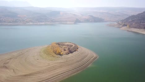 Green-Mountain-Reservoir-Island-aerial-trucking-pan-showing-dry-lake-bed-with-smoky-mountain-background